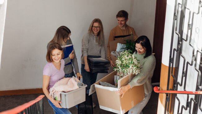 A group of people holding boxes in the hallway of the building as they move into a new home